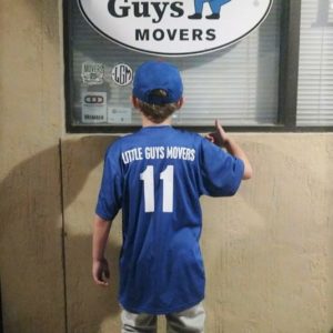 Little League player with Little Guys Movers on the back of shirt