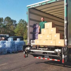 Little Guy standing in truck with boxes of food for Move For Hunger