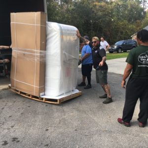 Four movers moving a hot tub into a truck