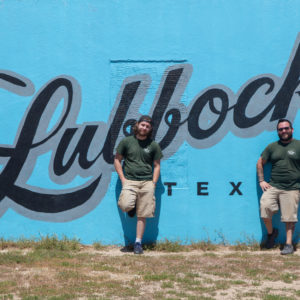 Three little guys employees in front of Lubbock mural in the arts district