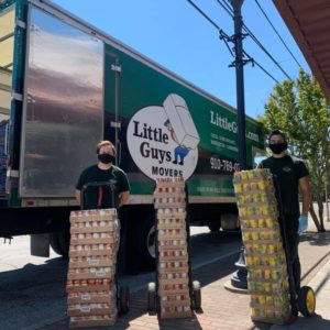 Little Guys Movers employees in front of truck with can food donations