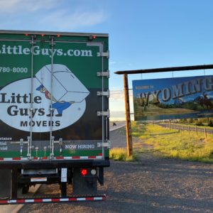 Little Guys Movers truck in front of Wyoming state sign