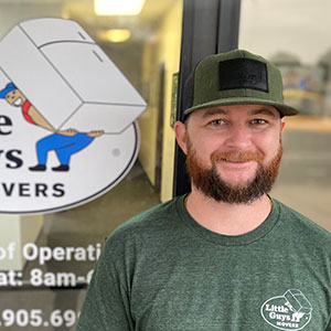 John, manager of Little Guys Movers in McKinney, stands in front of the office door