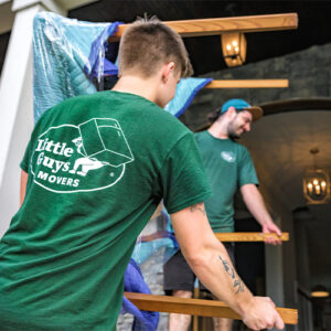 Two Little Guys Movers movers move a table together during a full-service move