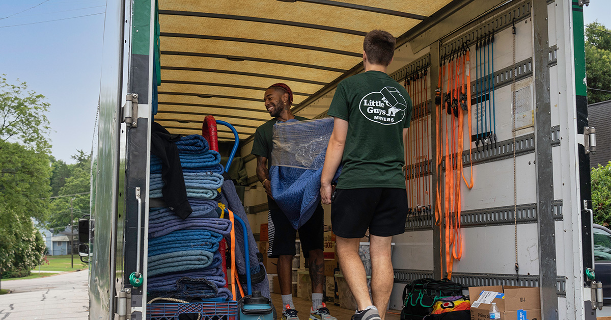 Two Little Guys Movers movers carefully move furniture into the moving truck.